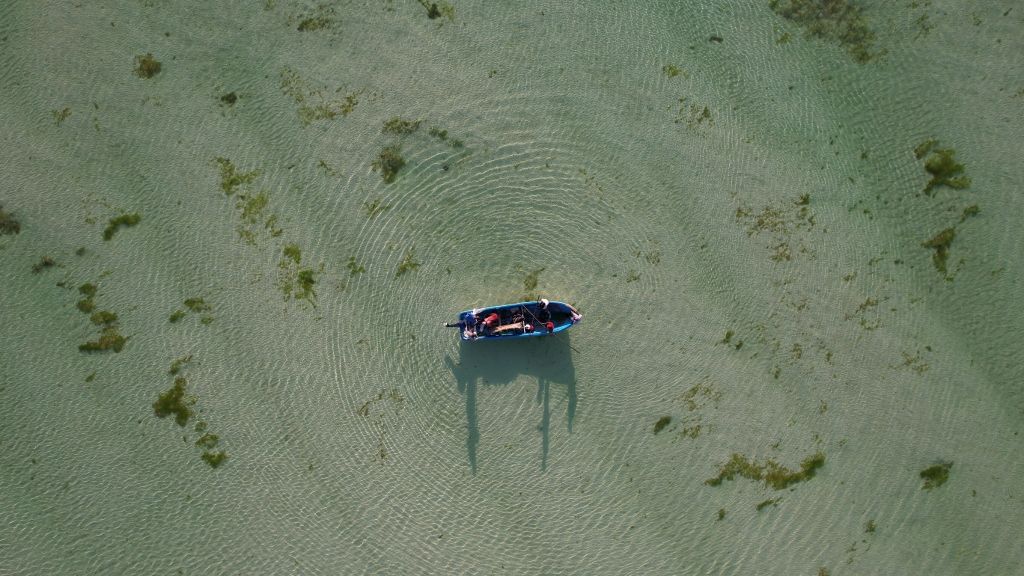 Aerial view of a single boat anchored in shallow seagrass water