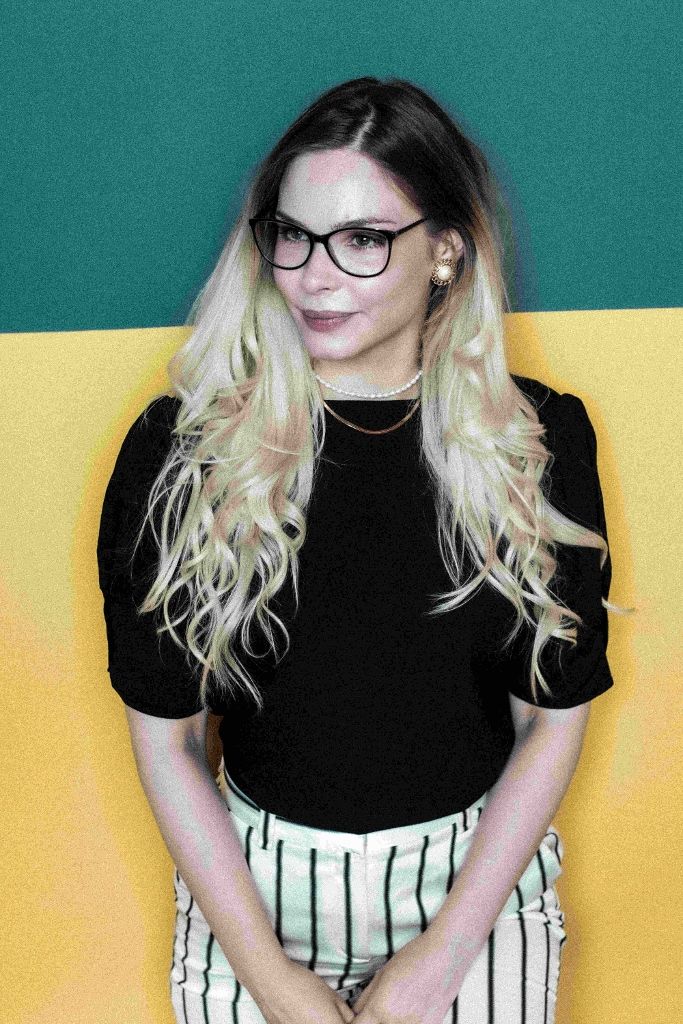 Studio portrait of a woman in glasses against a yellow and green backdrop