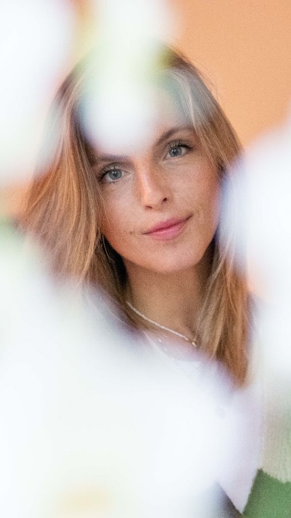 Soft focus portrait of a woman framed by out-of-focus white flowers