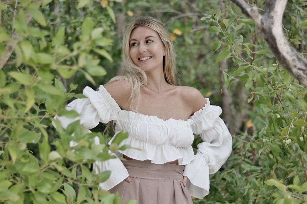 Outdoor portrait of a woman in a white ruffled blouse in greenery