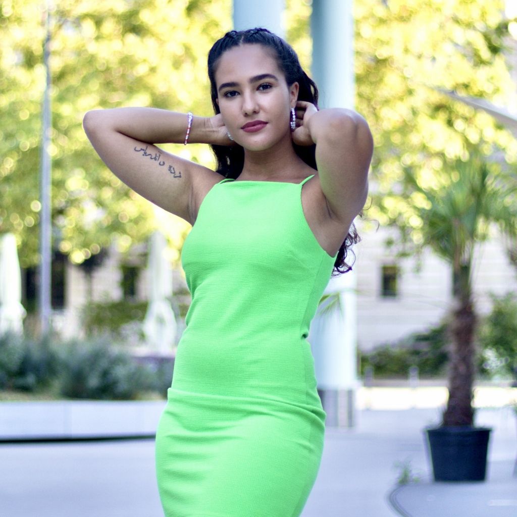 Outdoor portrait of a woman in a lime green dress in a city plaza
