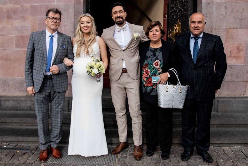 Wedding day group portrait of bride, groom, and parents on the church steps